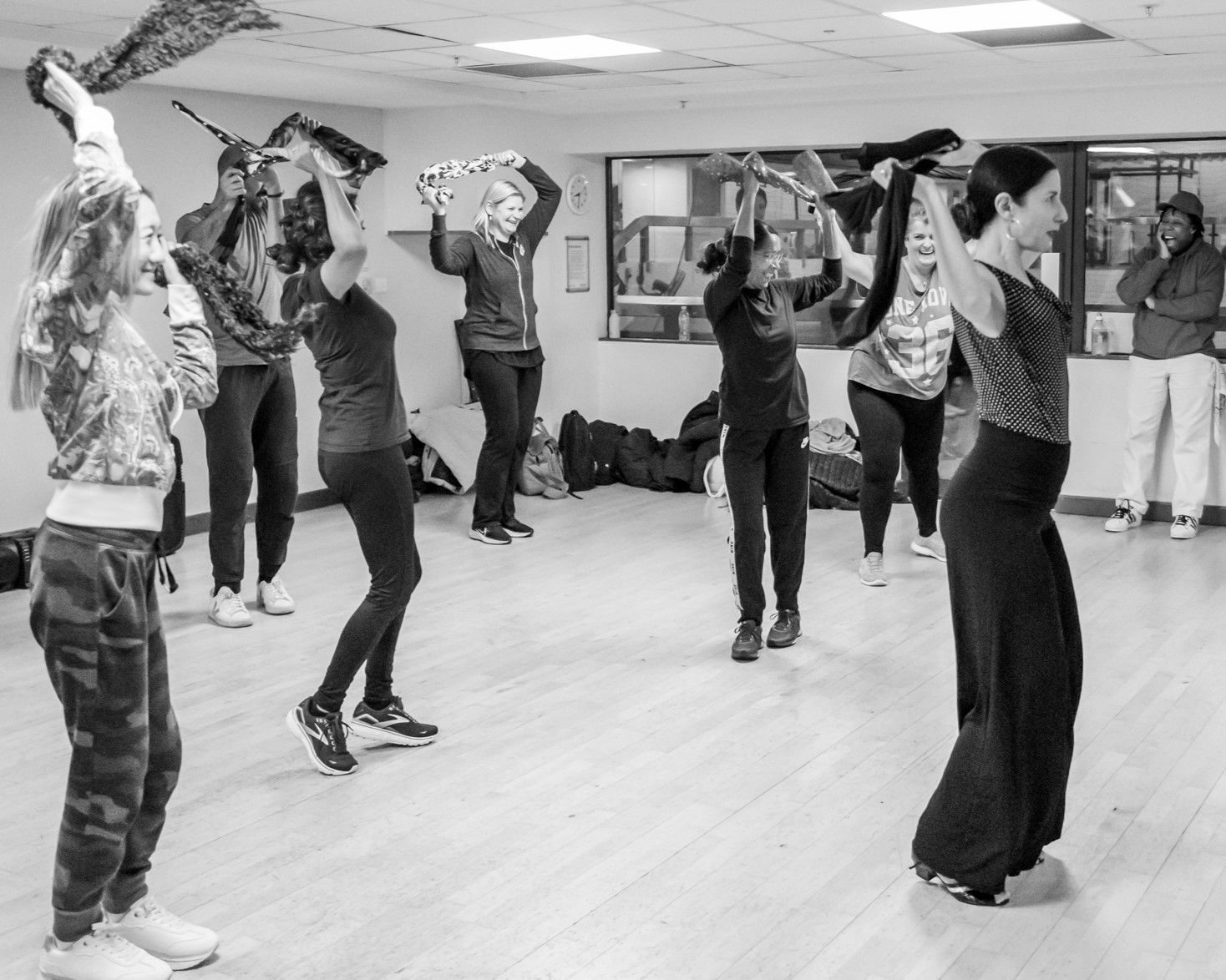 A black and white image of a group of people dancing and swirling a scarf over their heads.