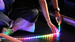 someone laying multi-coloured light strips on the floor