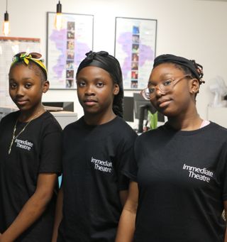 Four young people standing in a line, wearing black Immediate Theatre T-shirts
